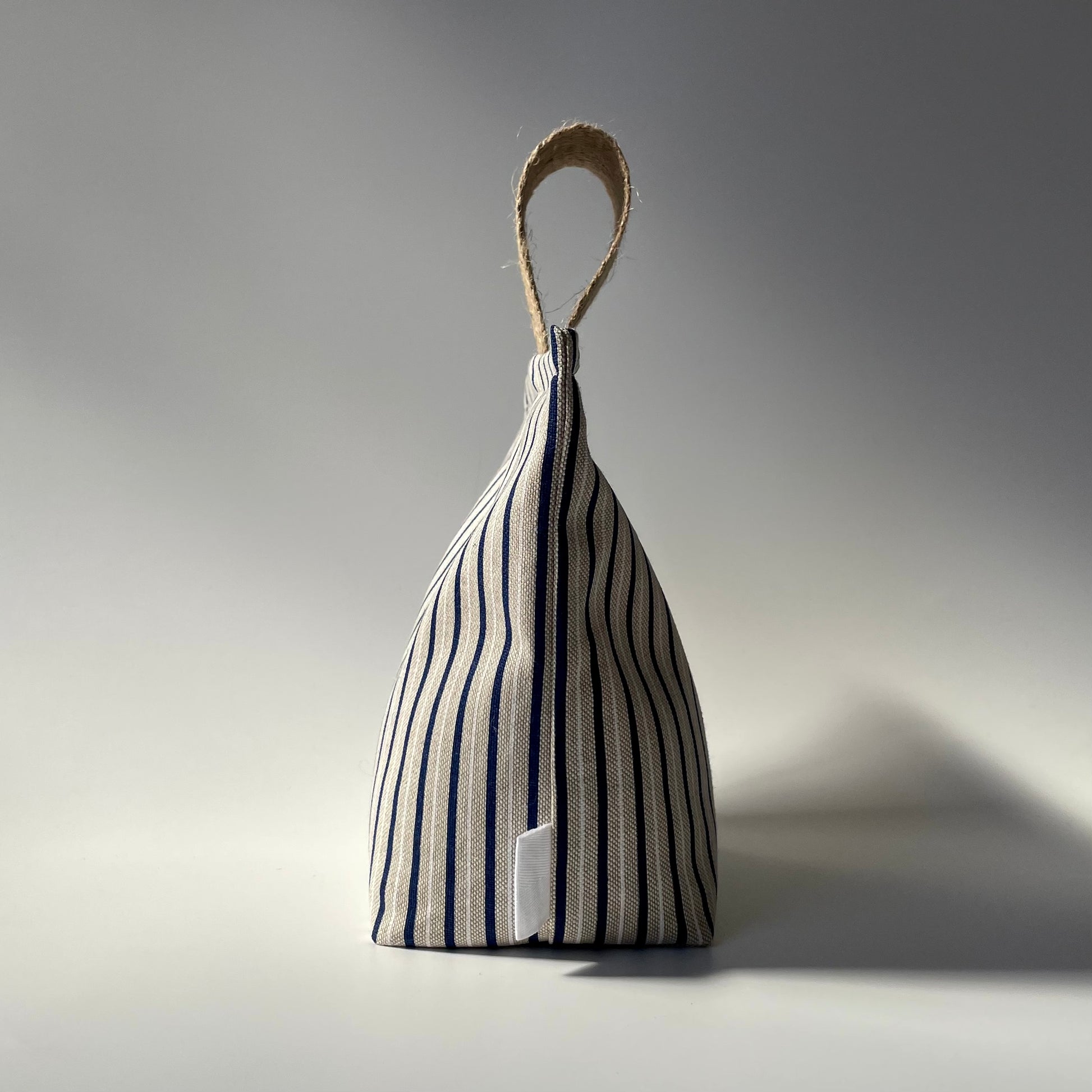 Blue and white stripe on beige background doorstop with jute handle.