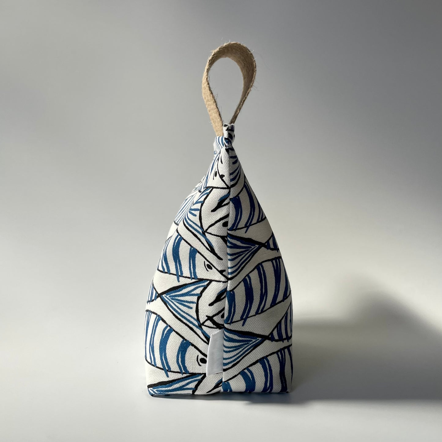 Fish Fabric Doorstop in white, blue and black Fabric Doorstop with thick jute handle on top.