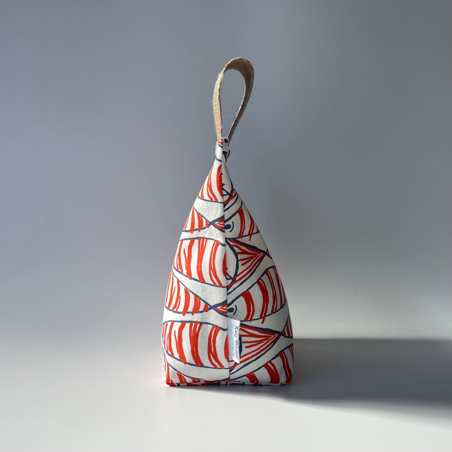 Fish Fabric Doorstop in white, orange and black Fabric Doorstop with thick jute handle on top.