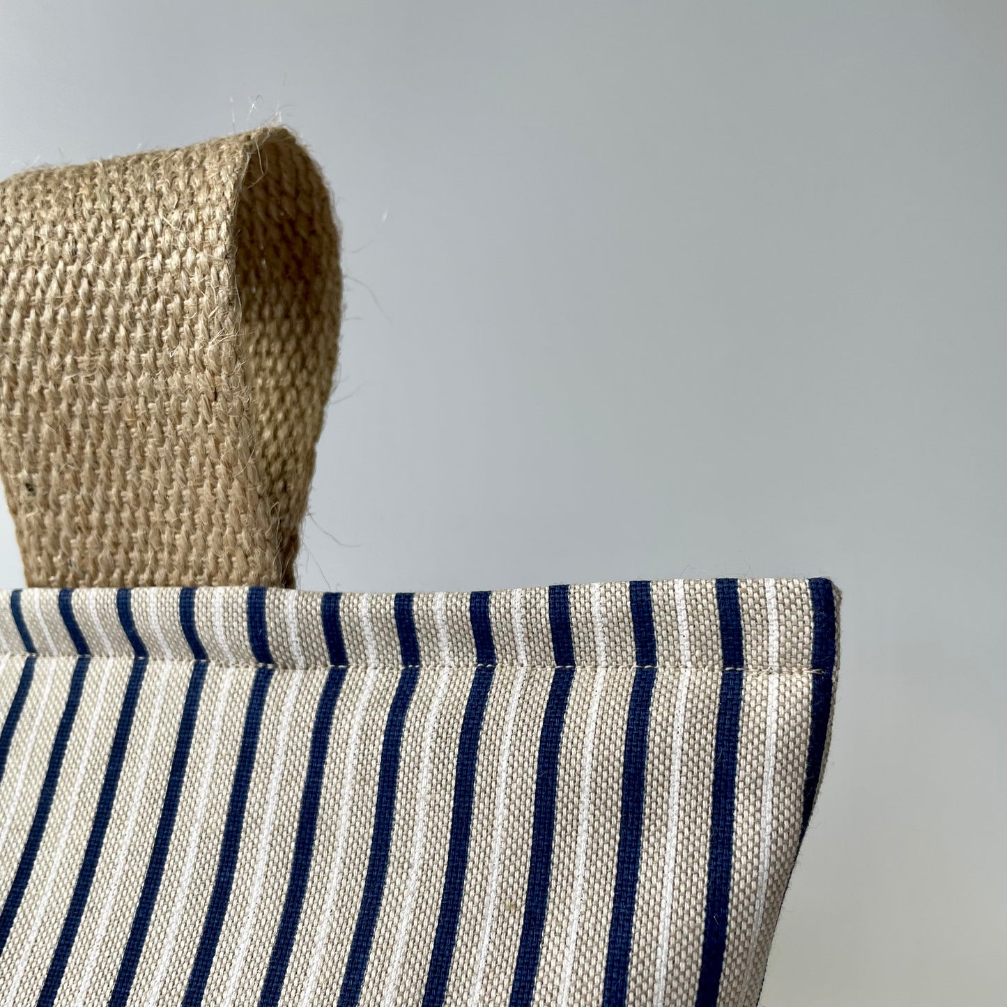 Nautical stripe doorstop with blue and white stripes on beige background - closeup of fabric and stitching.