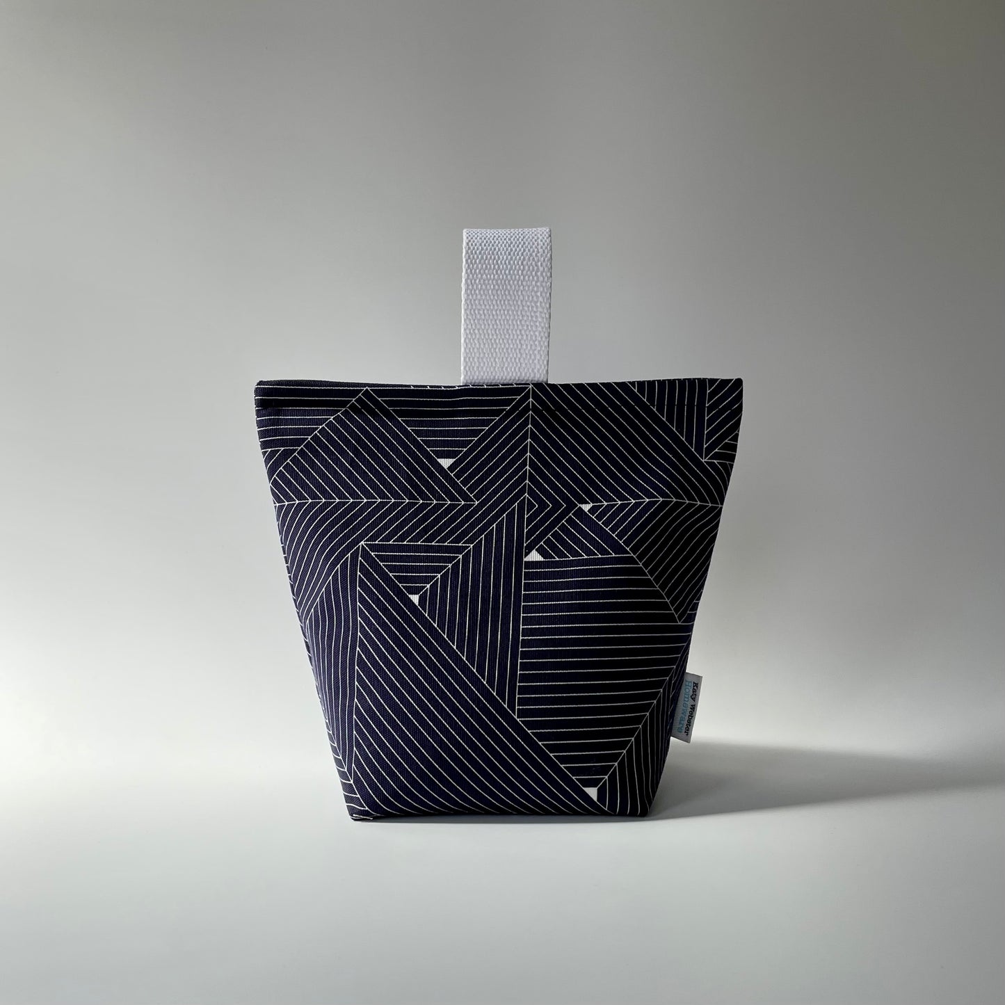 Navy blue and white grid patterned fabric doorstop with white webbed handle on top.