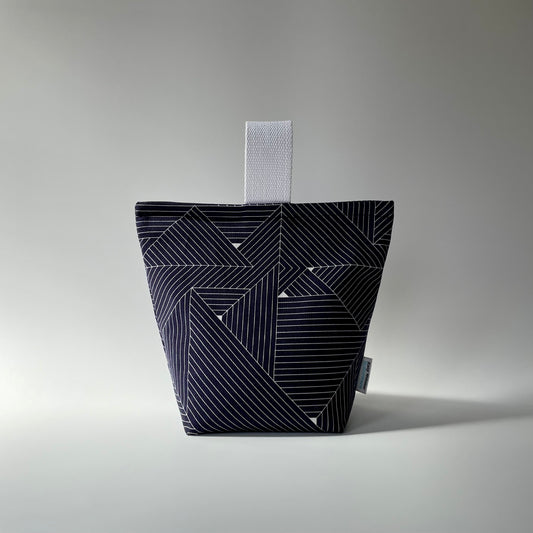 Navy blue and white grid patterned fabric doorstop with white webbed handle on top.