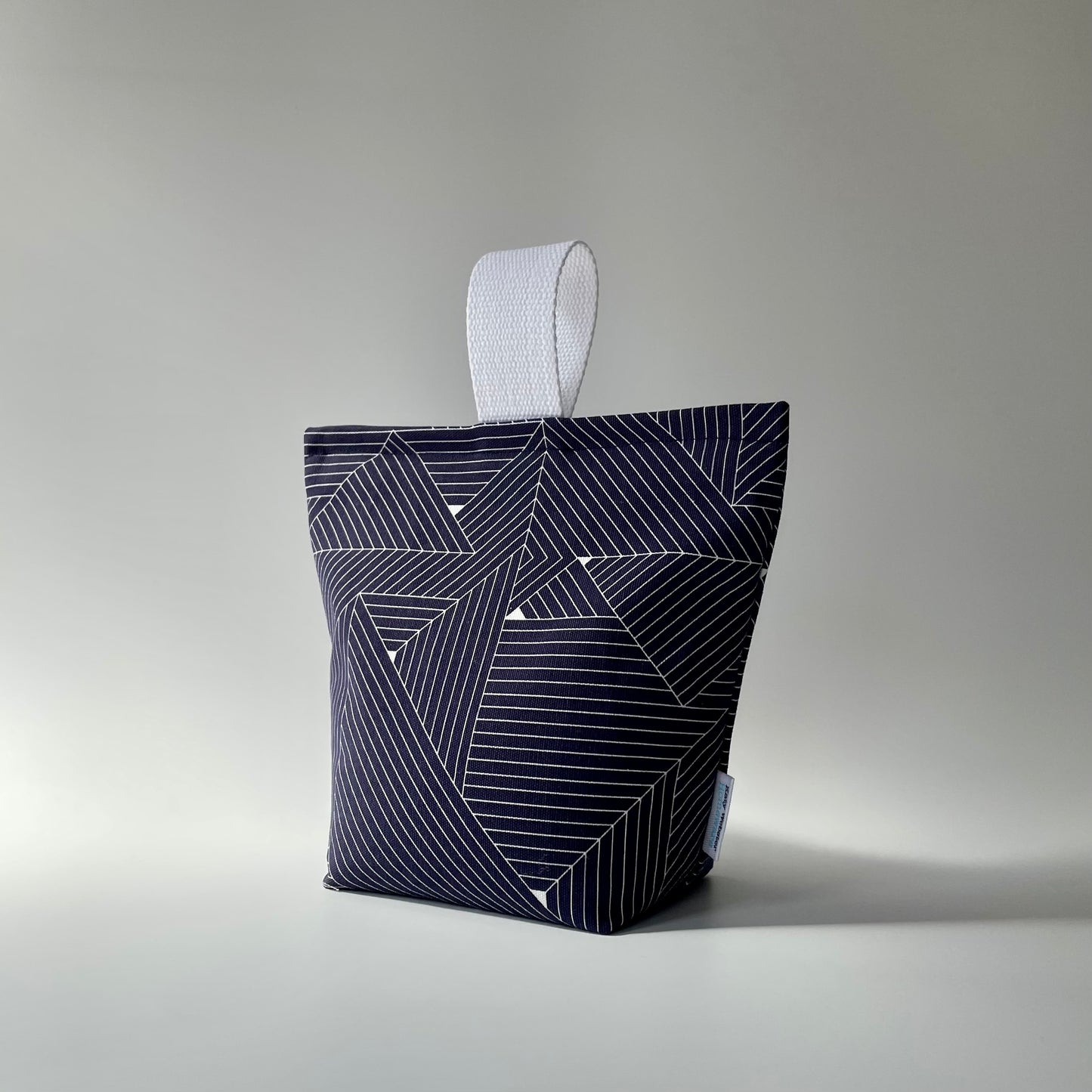 Navy blue and white grid patterned fabric doorstop with white webbed handle on top.