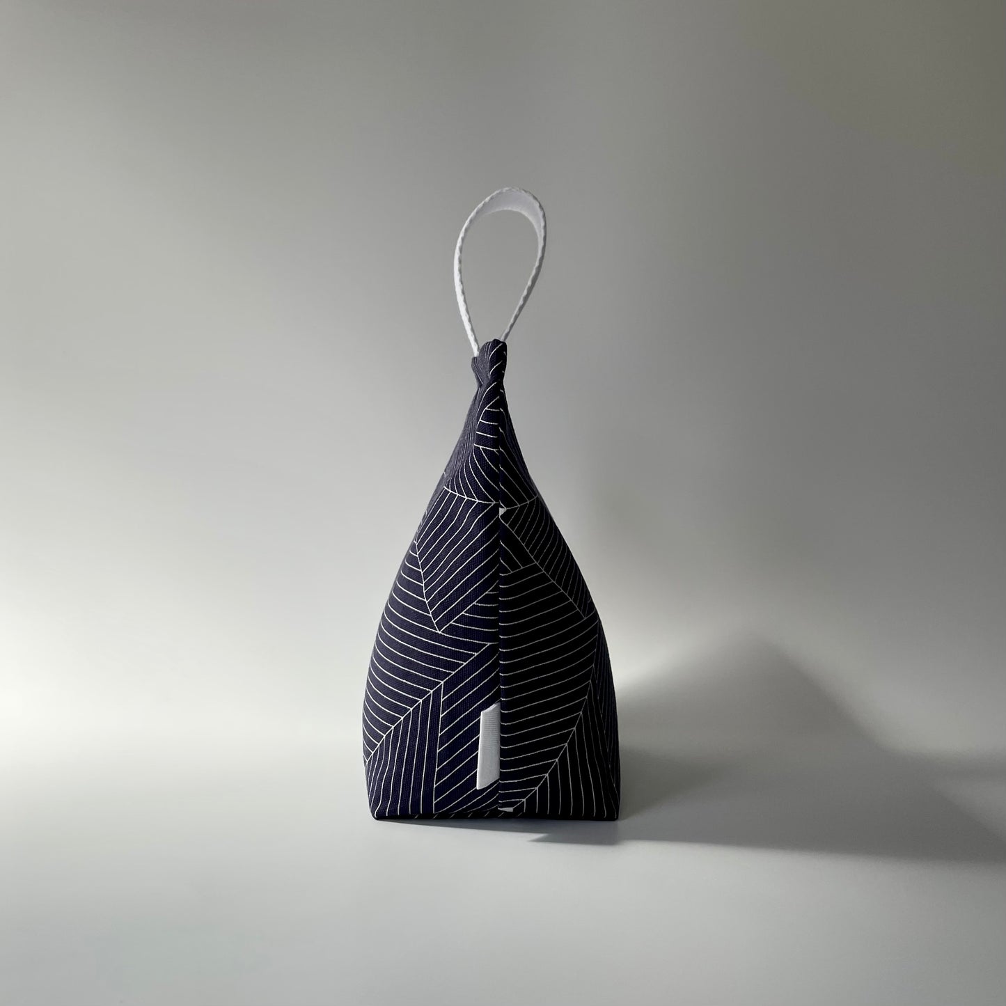 Navy blue and white grid patterned fabric doorstop with white webbed handle on top.
