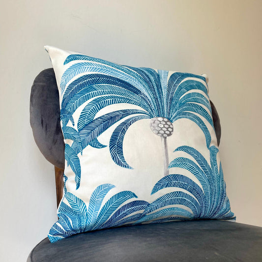 Decorative pillow with blue leaf pattern on a gray chair