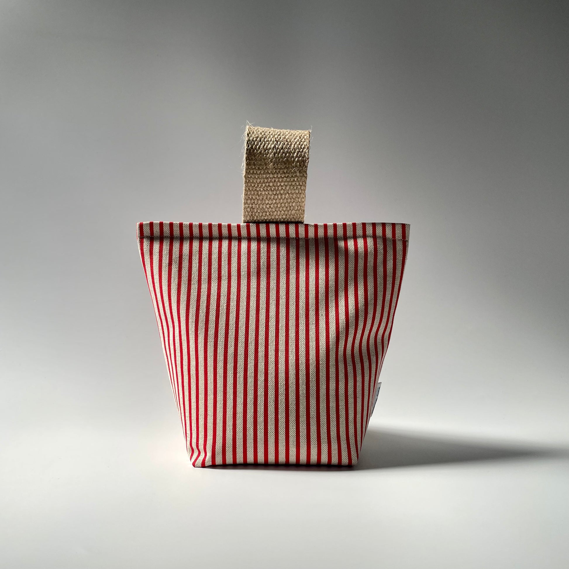 Red pinstripe on natural fabric doorstop with thick jute handle on top.