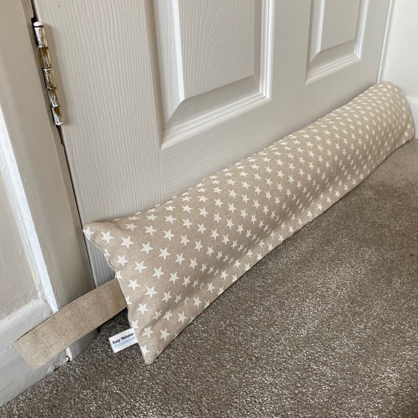 Heavy draught excluder with washable beige and white star print cover and hanging loop.