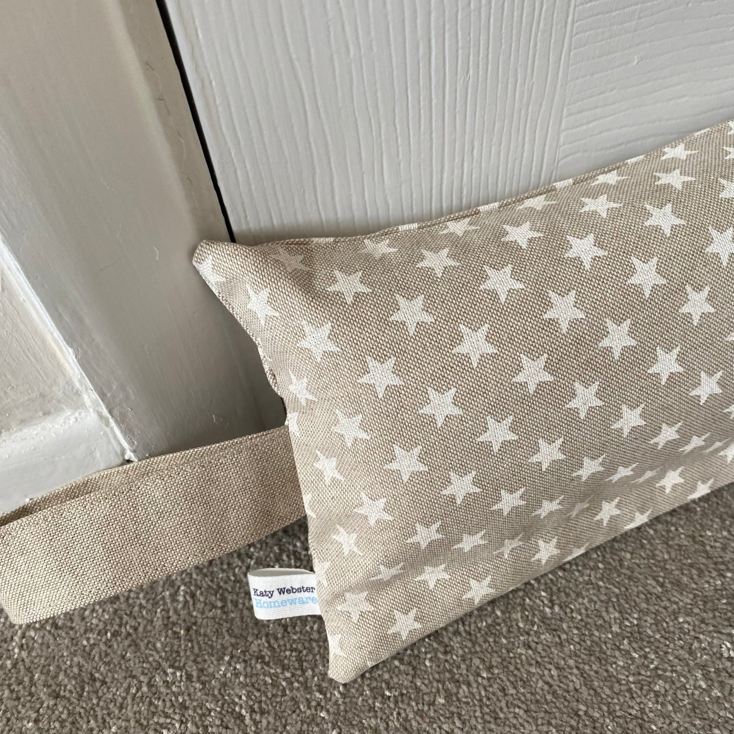Heavy draught excluder with washable beige and white star print cover and hanging loop.