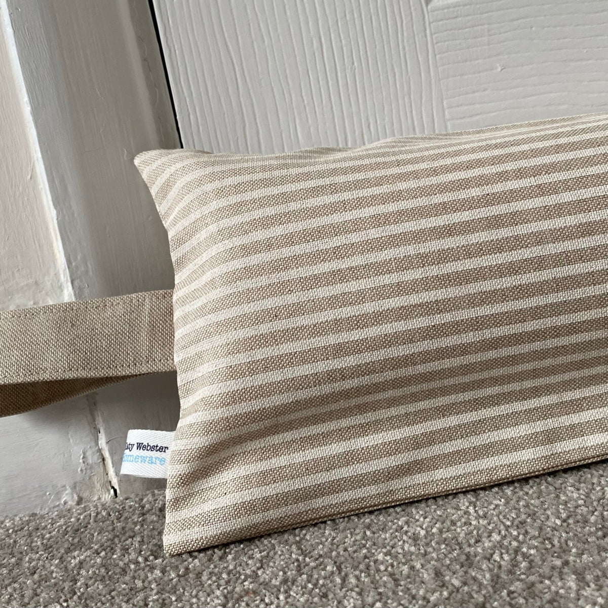 Heavy draught excluder with washable beige and white stripe cover and hanging loop.