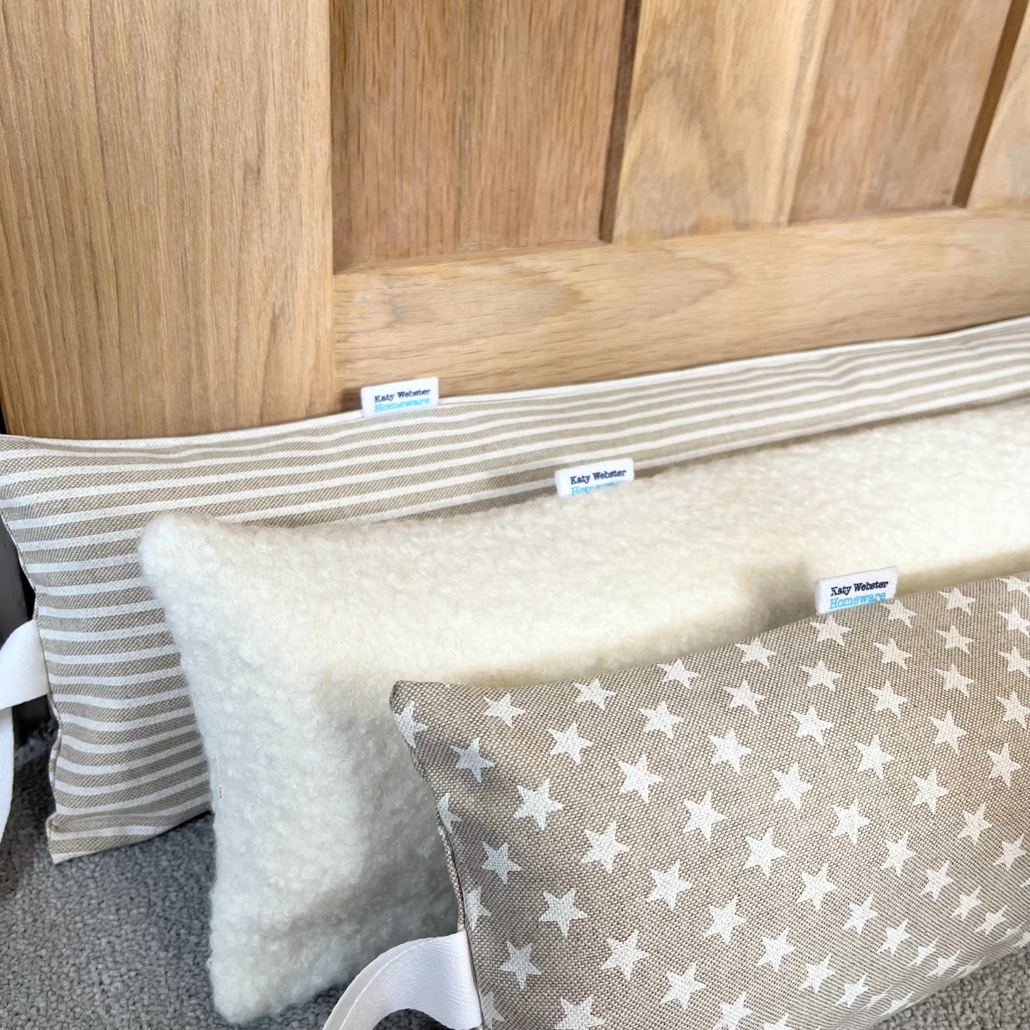 Draft Excluders against a door made with white star print, boucle and ticking stripe fabric.