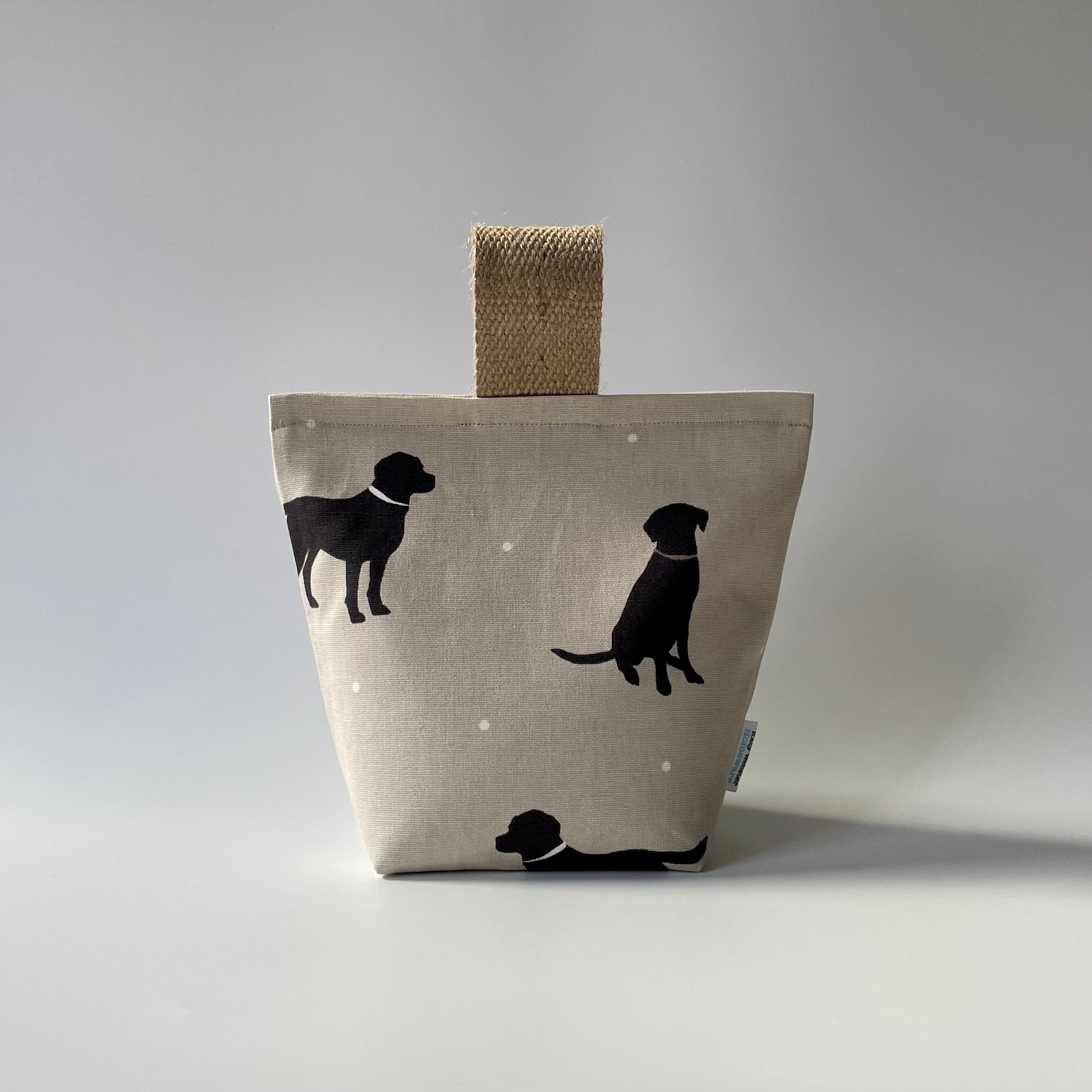 Black Lab print on taupe background with white dots fabric doorstop. Thick jute handle on top. 