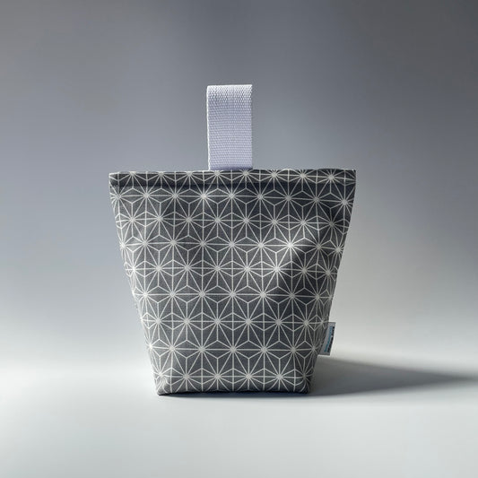 A grey geometric fabric door stop with a patterned design and a webbed handle.