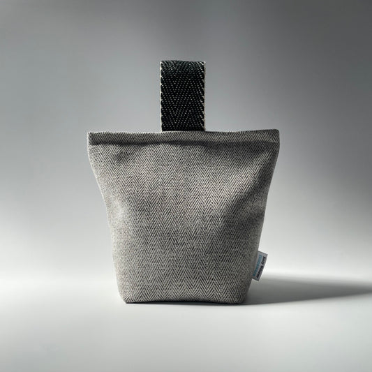 A grey herringbone pattern doorstop with a jute handle, lined with calico and filled with sand.