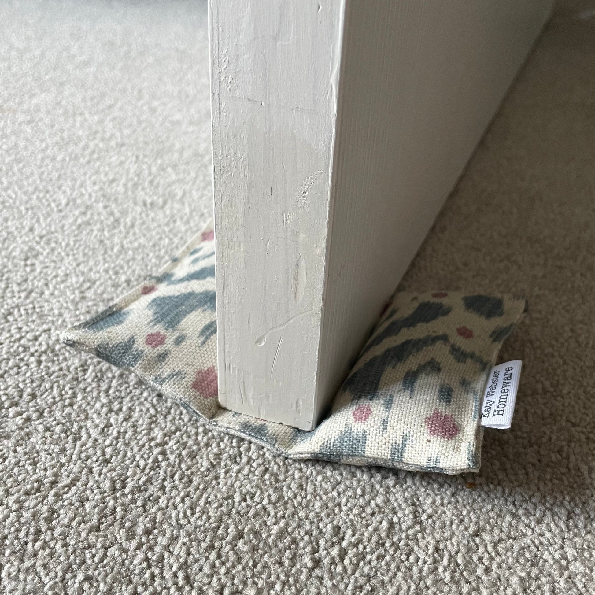 Ikat pattern pale blue and pink door wedge on a carpeted floor