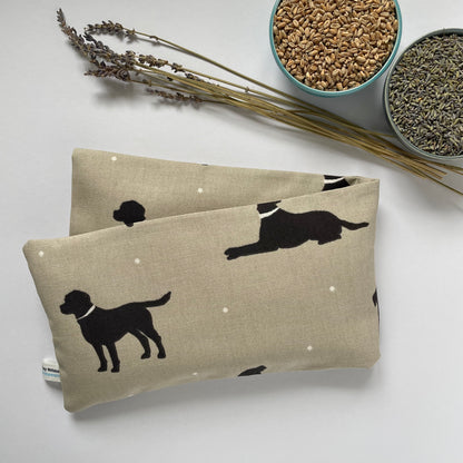Two beige fabric pouches with black dog illustrations on a light surface, accompanied by dried lavender and bowls of seeds.