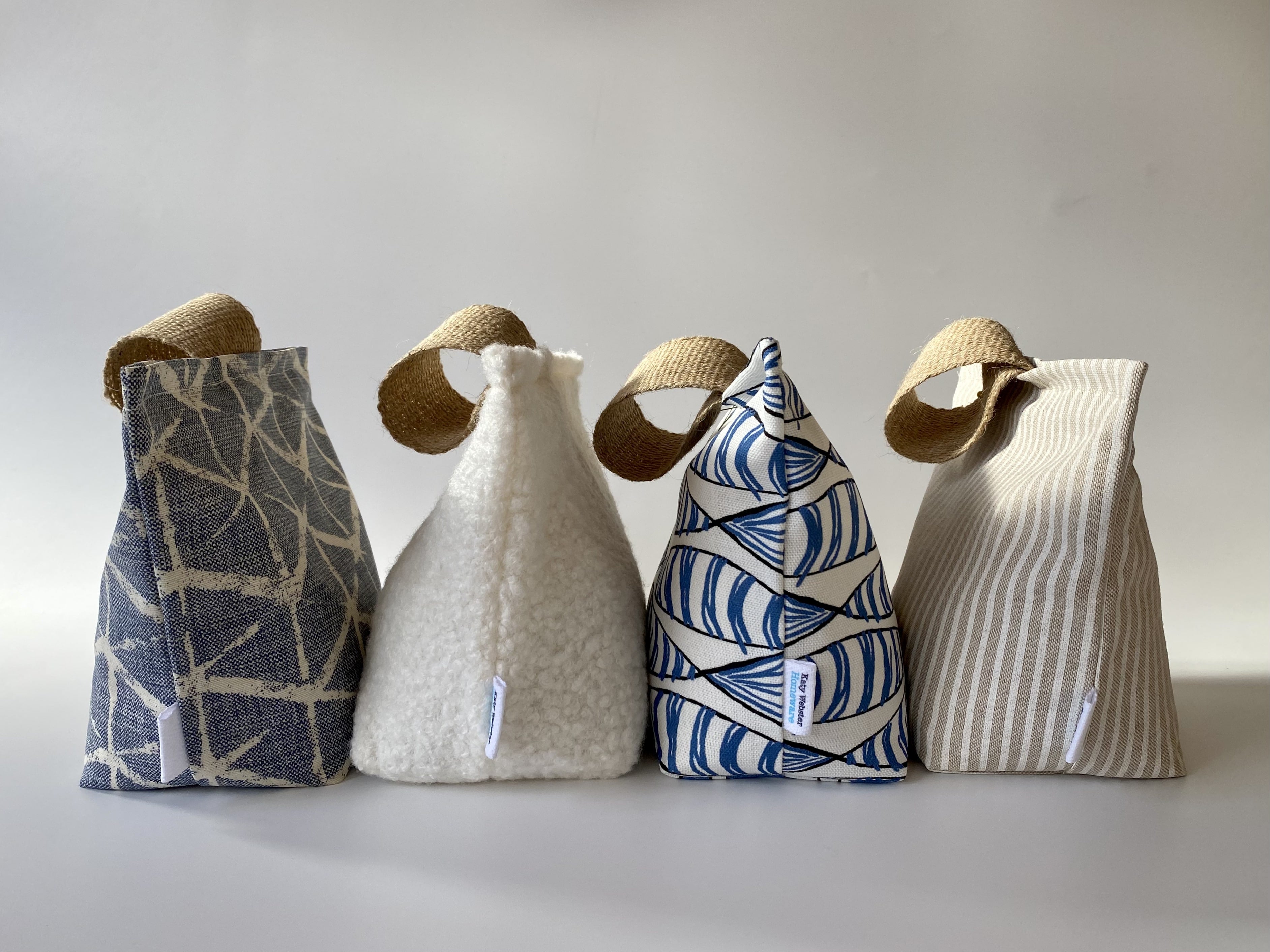 coastal fabric doorstop range featuring beach inspired fabrics and colours including geometric, boucle, fish print and stripe options. 