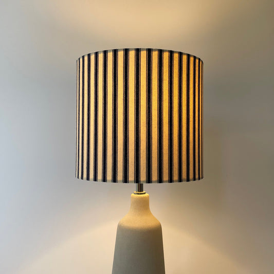 Navy and cream ticking stripe lampshade on a grey concrete lamp base