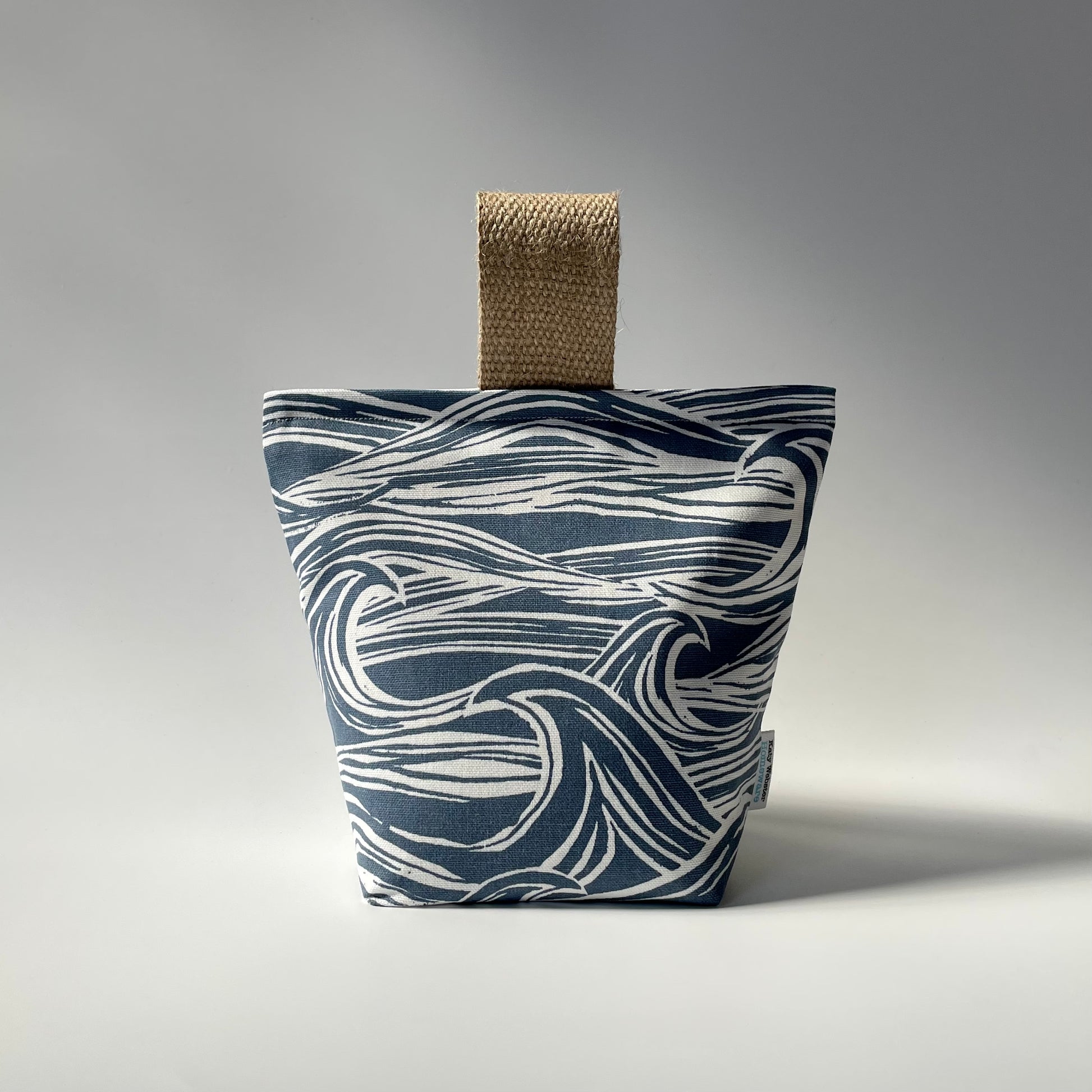 Fabric doorstop with a navy blue and white wave pattern, featuring a thick jute handle on top.