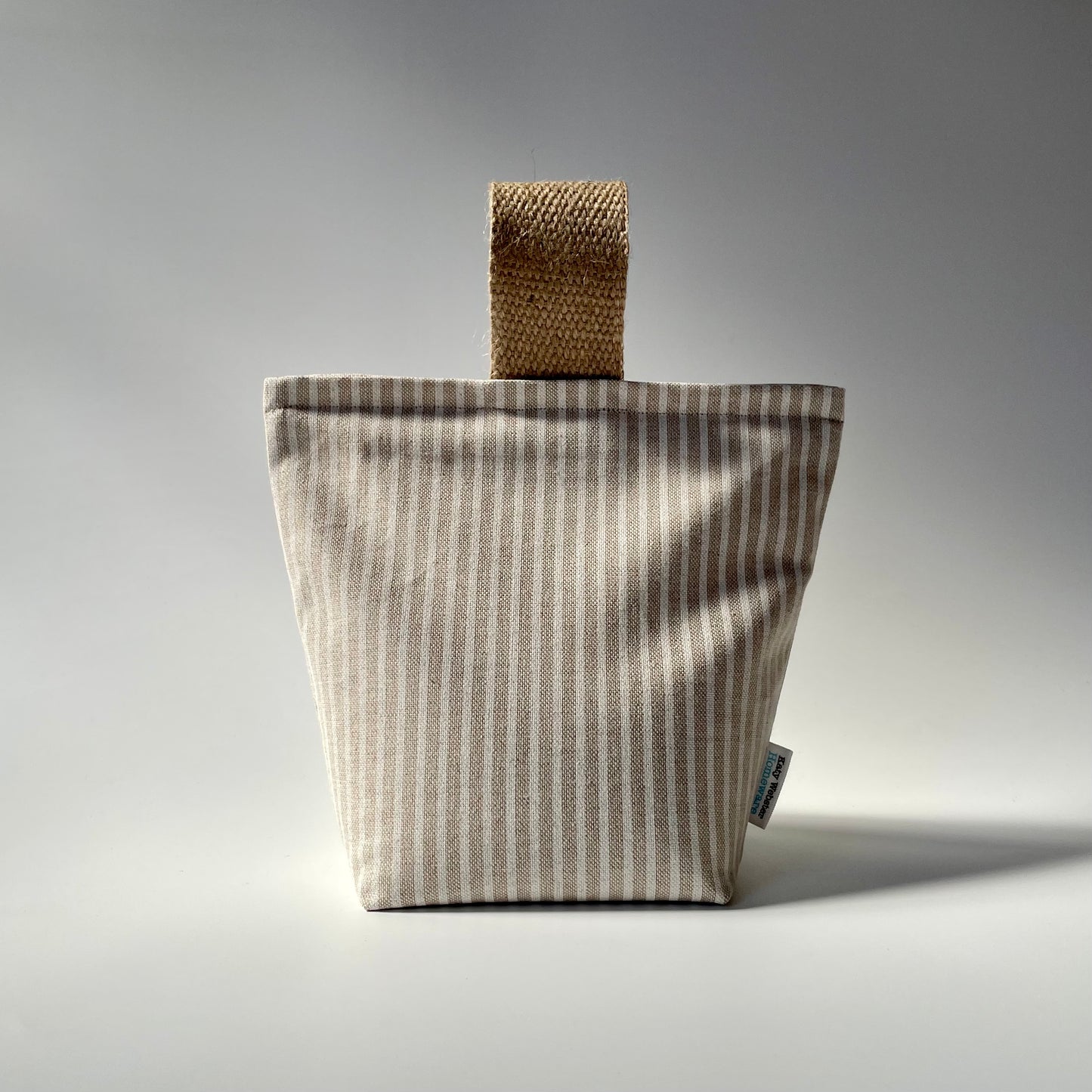 Fabric doorstop with a beige and white vertical pinstripe pattern, featuring a thick jute handle on top.