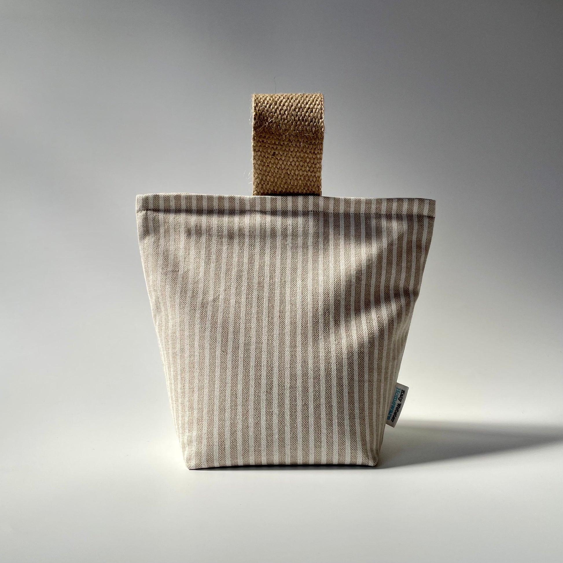 Fabric doorstop with a beige and white vertical pinstripe pattern, featuring a thick jute handle on top.
