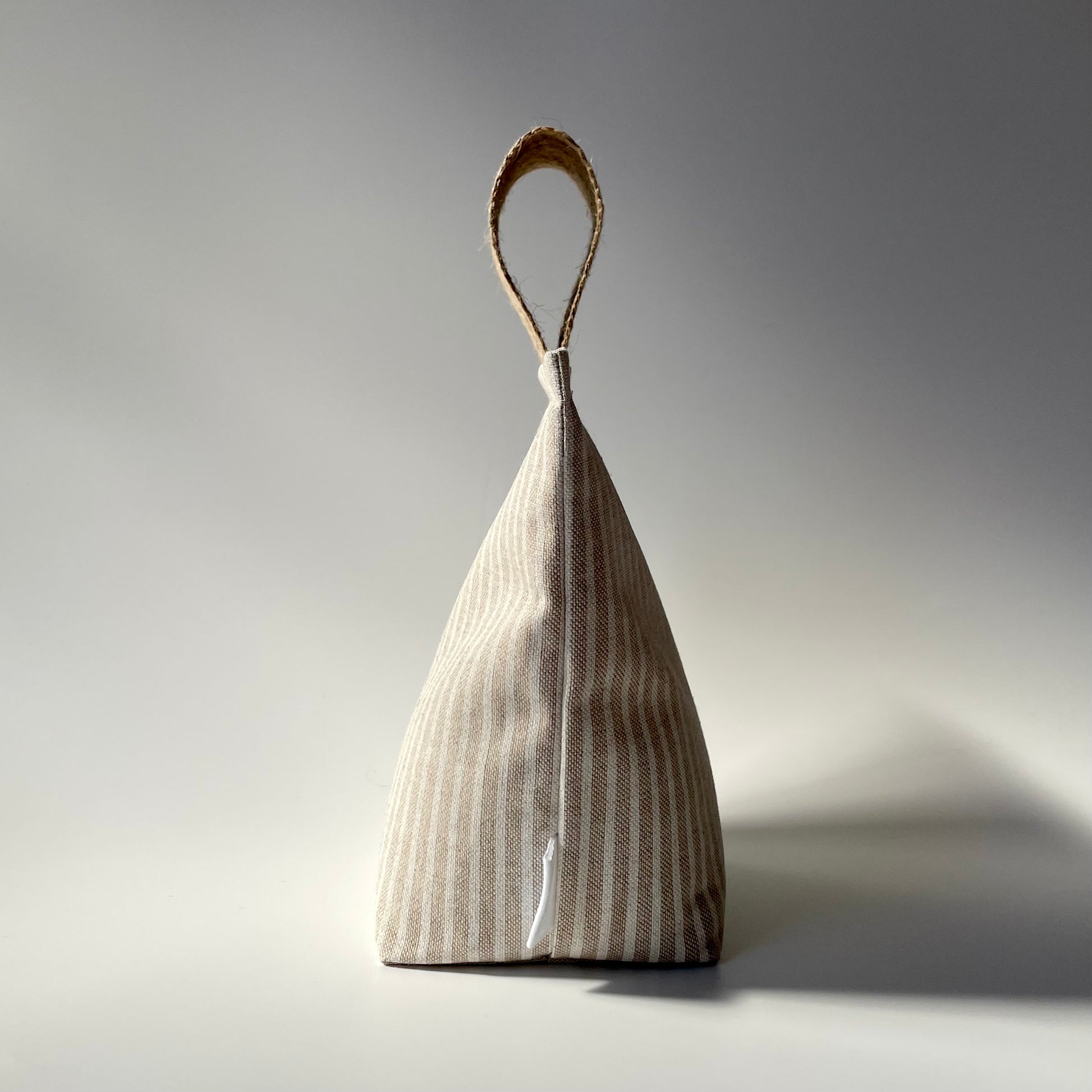 Fabric doorstop with a beige and white vertical pinstripe pattern, featuring a thick jute handle on top.