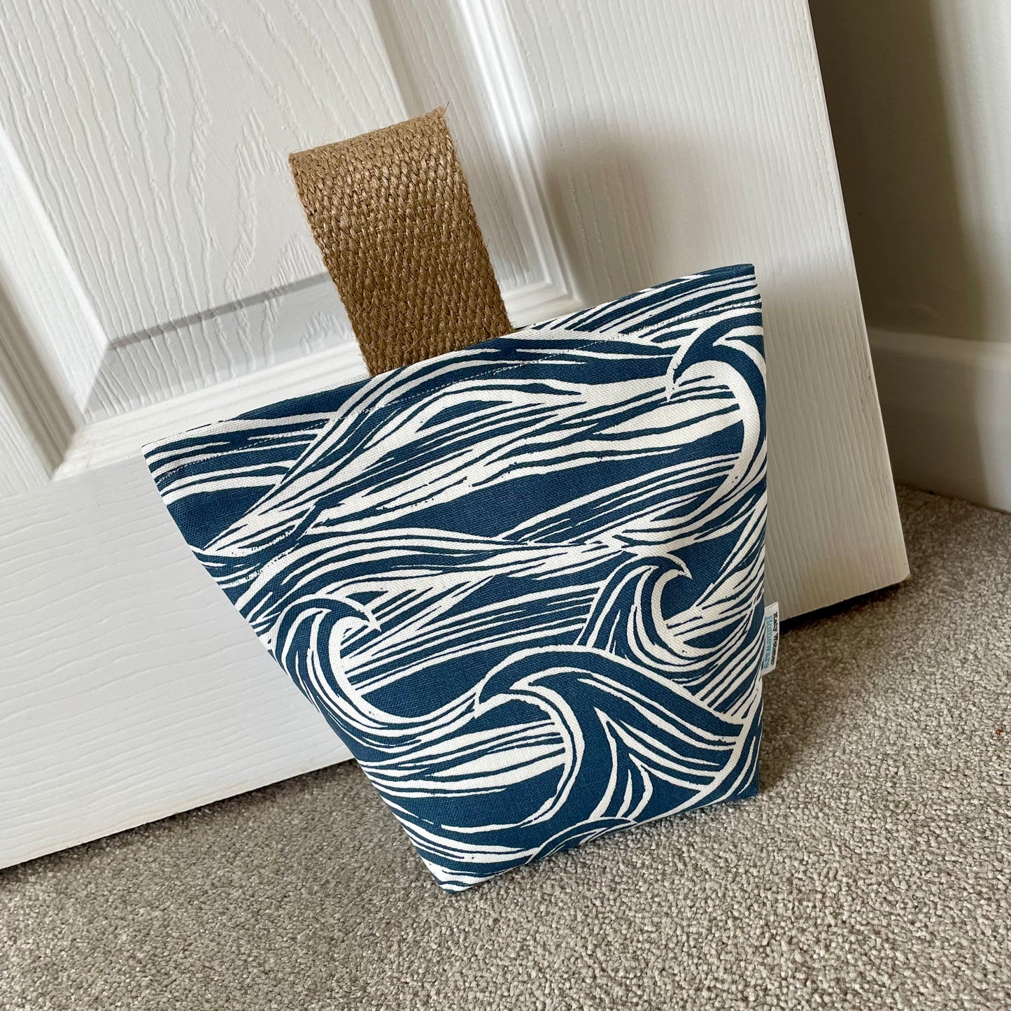 Sea Fabric Doorstop with jute handle shown in situ against base of door.