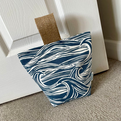 Sea Fabric Doorstop with jute handle shown in situ against base of door.
