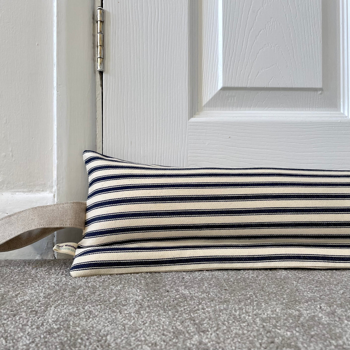 A striped navy blue and cream horizontal stripes, resting on a grey carpet in front of a white panelled door.