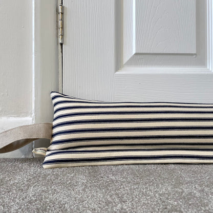 A striped navy blue and cream horizontal stripes, resting on a grey carpet in front of a white panelled door.