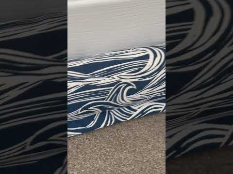 Navy and white wave-patterned draught excluder on a carpet floor next to a closed door.