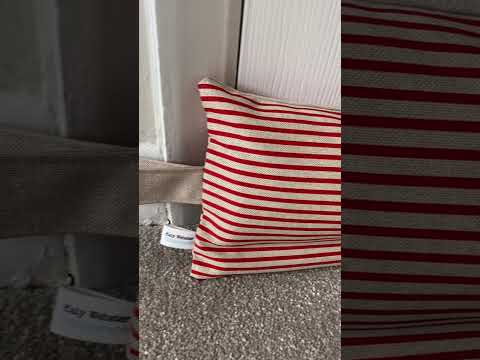 Red and beige stripe weighted draught excluder with washable cover and matching beige hanging loop.